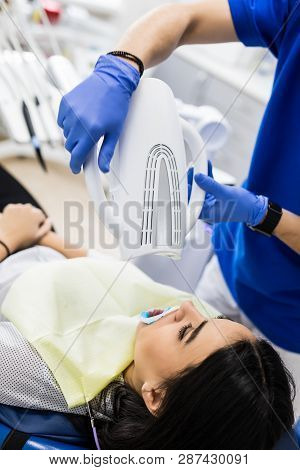 Teeth Whitening On Lamp Ultravioleta. The Girl On Reception At The Dentist For Teeth Whitening. The