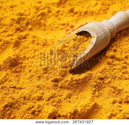 Wooden Scoop With Yellow Turmeric Powder Closeup, Abstract Grocery Background