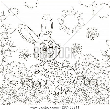 Little Bunny Coloring A Big Easter Egg On Grass Among Flowers On Its Front Lawn Near A Small Hut Wit