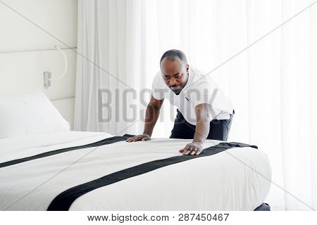 Maid Making Bed In Hotel Room. Staff Maid Making Bed. African Housekeeper Man Making Bed.