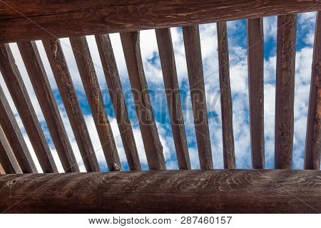 View Of Blue Sky And Clouds Through Lattice Over Exposed Vigas, Adobe Construction, Horizontal Aspec