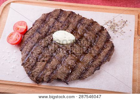 Prepared Steak Served With Butter On Wooden Board
