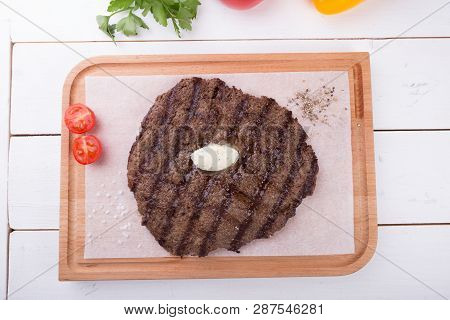 Prepared Steak Served With Butter On Wooden Board