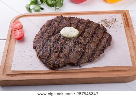 Prepared Steak Served With Butter On Wooden Board