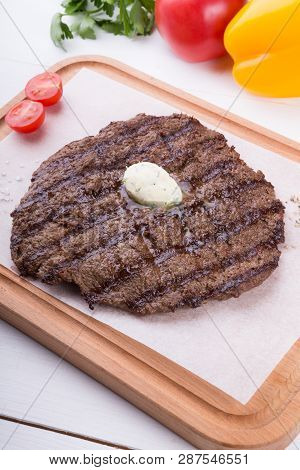 Prepared Steak Served With Butter On Wooden Board