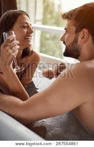 Attractive young couple drinking champagne in the bathtub
