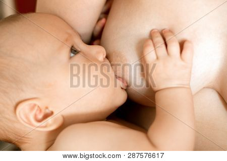 Mother Breast Feeding and Hugging Baby. Mother Holding NewBorn in Embrace and Breastfeed