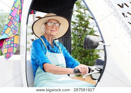 Portrait Of Cheerful Senior Woman Driving Bicycle Car In Garden Or Plantation, Copy Space