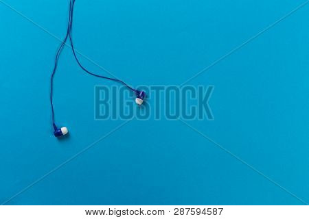 Small Black Earphones On Blue Background- Image