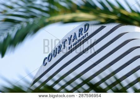 Batumi, Georgia, 2018-10-10: Marriott Courtyard Sign Surrounded By Palm Leaves. Marriot Hotel Buildi