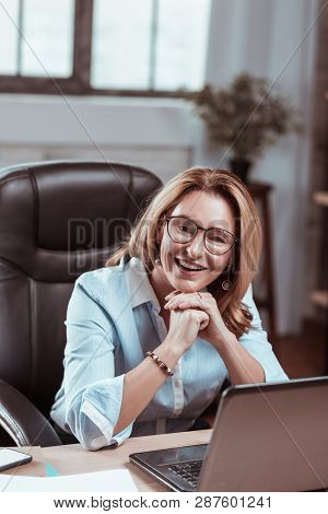 Appealing Mature Woman Wearing Nice Earrings Smiling At Work