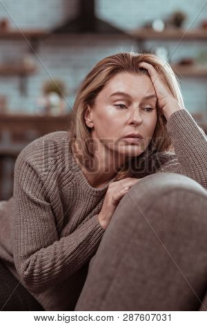 Dark-eyed Woman Sitting On Sofa And Feeling In Despair