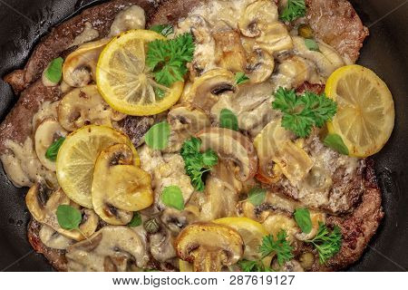 A Closeup Photo Of Scallopine Di Vitello, Veal Scallopini, With A Mushroom Sauce, Lemons, And Parsle
