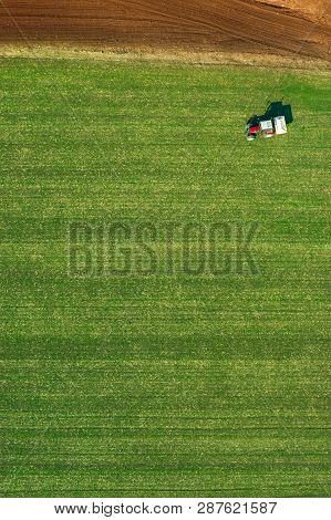 Agricultural Tractor Is Fertlizing Wheat Crop Field With Npk Fertilizers, Aerial View From Drone Pov