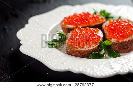 Red Caviar On Black Bread With Butter. Healthy Food. Fish Appetizer. Dark Background