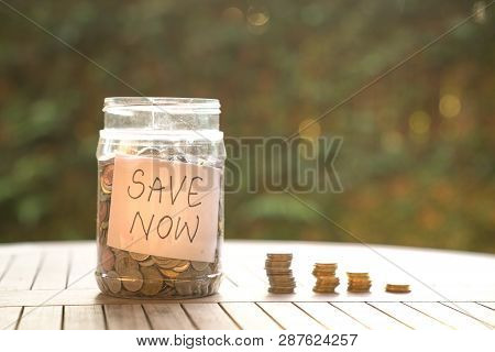 Save Money Concept: Coins Stored In Container And Stacked On Table