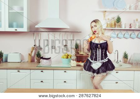 A Blond Woman Eats Cookies In The Kitchen.