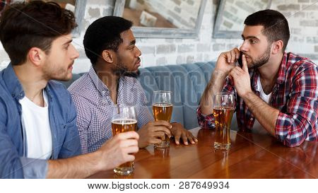 Let Me Talk On Phone. Man Asking For Silence, Sitting In Bar With Friends