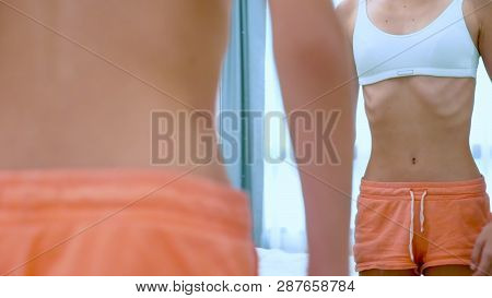 Anorexia Concept - Slim Teen Girl, With Protruding Ribs Looking At Her Reflection In The Mirror