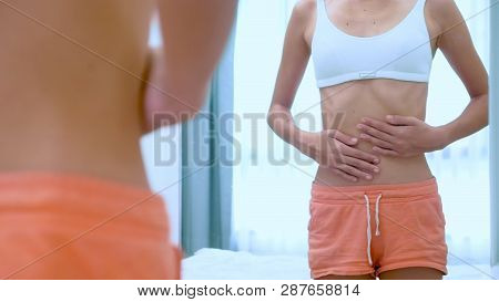 Anorexia Concept - Slim Teen Girl, With Protruding Ribs Looking At Her Reflection In The Mirror