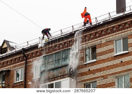 Tyumen, Russia - February 19, 2019: Men With Snow Shovels Clean Residential Building Roof In Winter 