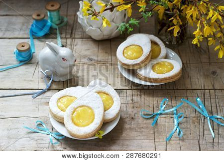 Easter Composition With Egg-shaped Cookies Filled With Lemon Curd, Rabbit, Bouquet Of Forsythia And 