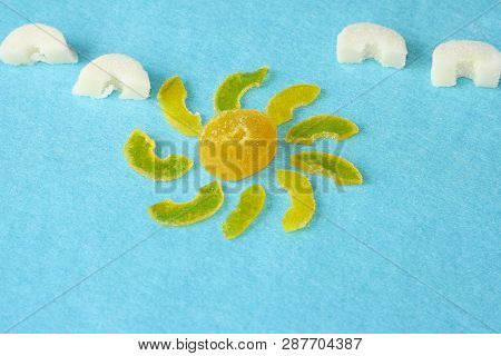 Sun From Yellow Marmalade With Rays And White Marmalade Clouds On A Blue Felt Background. Sugar Swee