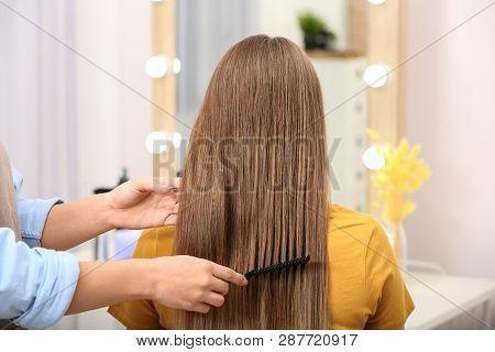 Professional Coiffeuse Combing Client's Hair In Salon