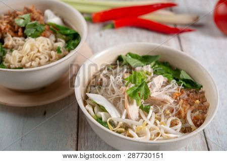 Asian soup noodles with chicken in bowl on wooden table. 