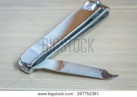 Top View Of A Nail Cutter Nail Trimmer Nail Shaper Kept On A Wooden Table. Copy Space Provided