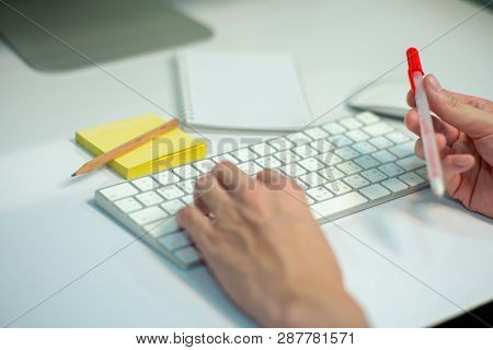 Selective Focus On White Keyboard Of Desk Top With Blurred Motion Of Hands Spinning The Pencil In Fo