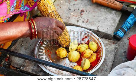 Street Vendor Is Rubbing A Roasted Sweet Corn Cob With Lemon And Spices.
