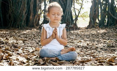 Little Child Girl Meditating Alone Under Banyan Tree