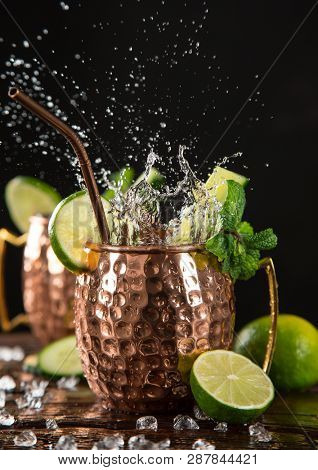Famous splashing Moscow mule alcoholic cocktail in copper mugs, freeze motion effect.