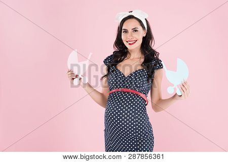 Brunette Pregnant Woman Holding Paper Stollers With Smile Isolated On Pink