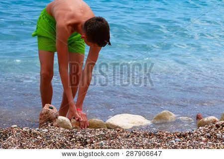 Active Children Summer Vacation At Sea. Healthy Sunburnt School Boy In Green Shorts Is Relaxing On S