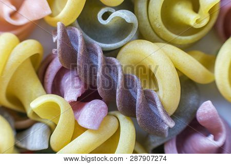 Close-up Of Raw Dry Uncooked Colorful Noodles Pasta Abstract Background. Italian Traditional Cuisine