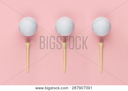 Abstract golf concept with three wooden tee and white golf ball isolated on pink