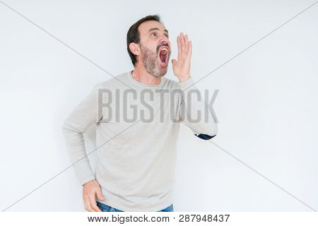 Elegant senior man over isolated background shouting and screaming loud to side with hand on mouth. Communication concept.