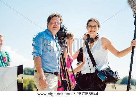 Film or video crew with cameraman and sound engineer during production looking into camera