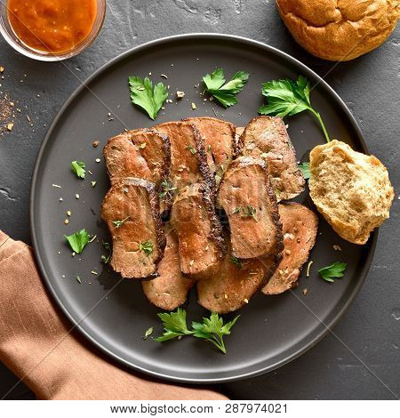 Close Up Of Grilled Sliced Beef Liver On Plate Over Black Stone Background. Cooked Liver(offal) From