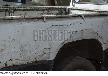 The Body Of An Old Pickup Truck With Cracked Paint. Rusty Car In The Parking Lot. Vintage Commercial