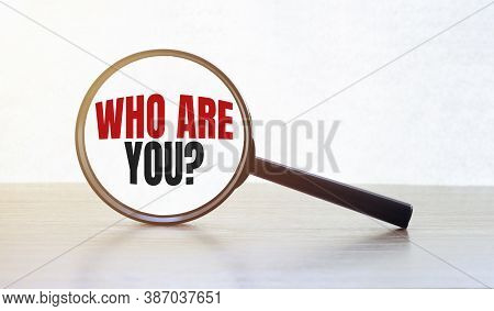 Magnifying Glass With Text Who Are You On Wooden Table.