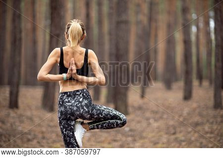 Beautiful Woman Standing And Doing Yoga In Forest. Exercise And Meditation Concept. Pay Obeisance Or