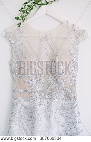 Close-up Of A White Corset Of A Bridesmaid Dress With Patterns On A Hanger On A White Background.