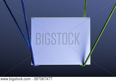 Blank White Foursquare Signage Template On Dark Background Illuminated By Light And Tied With Ropes.