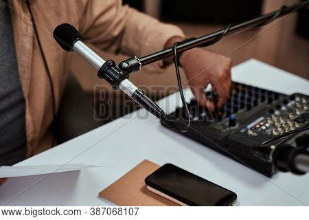 Close Up Of Microphone At Radion Station Studio. Male Host Working On A Sound Mixing Desk In Studio,