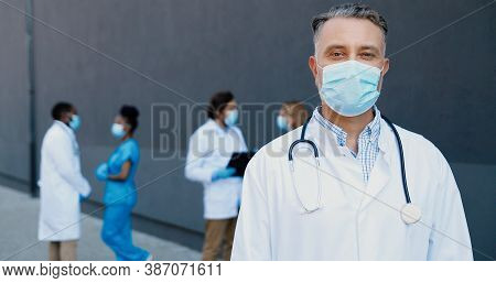 Portrait Of Caucasian Good-looking Man Doctor In Medical Mask And With Stethoscope Looking At Camera