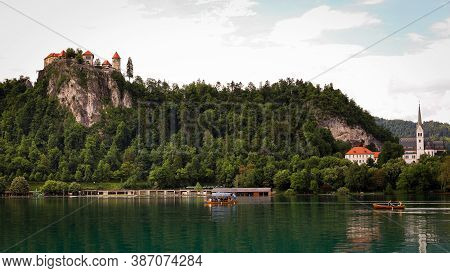 View Of The Bled Castle And Church With Boats On The Lake In The Foreground