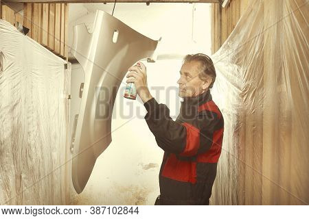Man Spraying And Repairing In Basement Car Fender For Replacing